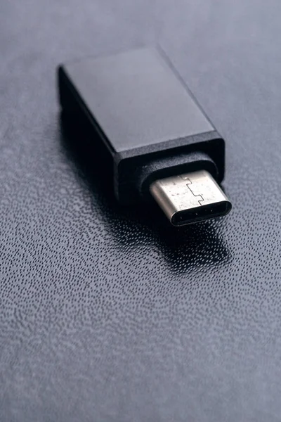 Black USB OTG (USB on The Go) with USB Type C port for connection betwen cellphone and flash disk drive on black background