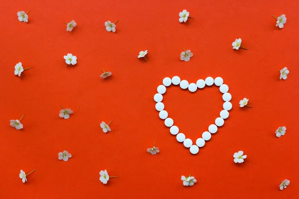 Heart shape made of white pills with white flowers pattern on or — Stock Photo, Image