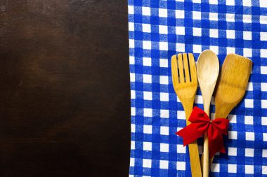 Wooden table with checked tablecloth and wooden kitchen utensils
