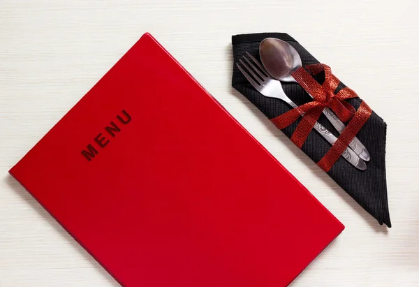 Prataria com arco vermelho no guardanapo preto ao lado do menu — Fotografia de Stock