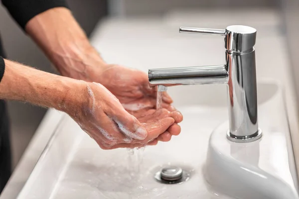 Handen wassen man spoelen zeep met stromend water op spoelbak, Coronavirus preventie handhygiëne. Corona Virus pandemische bescherming door het reinigen van handen vaak — Stockfoto