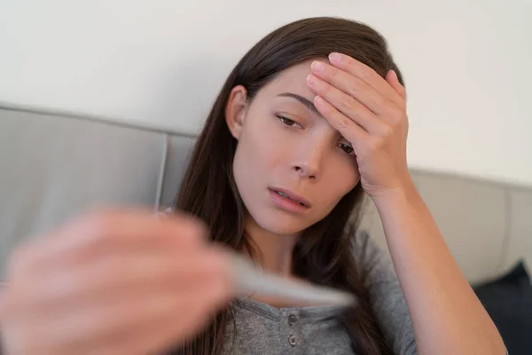 Coronavirus koorts symptoom Aziatische vrouw controleren hoge temperatuur met thermometer. Corona virusinfectie veroorzaakt respiratoire ziektesymptomen zoals hoesten, hoofdpijn en in ernstigere gevallen longontsteking — Stockfoto