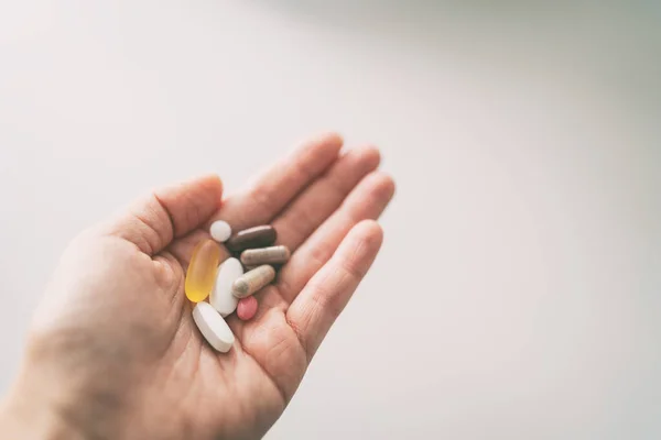 Vitaminas, minerales y suplementos píldora cápsulas mujer tomando muchas píldoras vista superior de las tabletas de mano — Foto de Stock