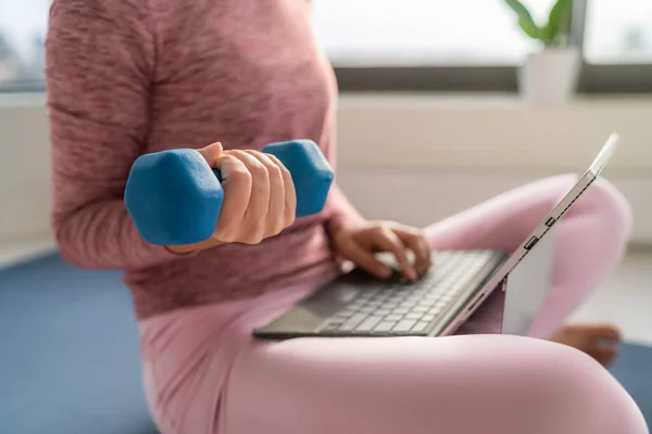 Trening fitness i praca na laptopie - kobieta wielozadaniowa zdalna praca w domu w domu podnoszenie hantli do treningu siłowego w środku — Zdjęcie stockowe