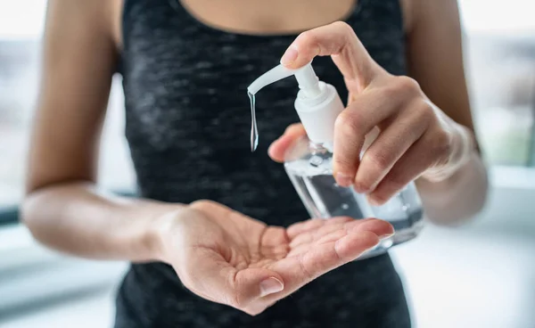El dezenfektanı kadın jel sıvısı uyguluyor ellerini ovuyor evde kişisel hijyen koronavirüsünü temizliyor. Dezenfekte edici şişe — Stok fotoğraf