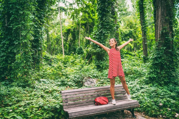 Mujer asiática feliz disfrutando de la libertad en verano árboles naturales de pie en el banco del parque con los brazos extendidos en la alegría —  Fotos de Stock