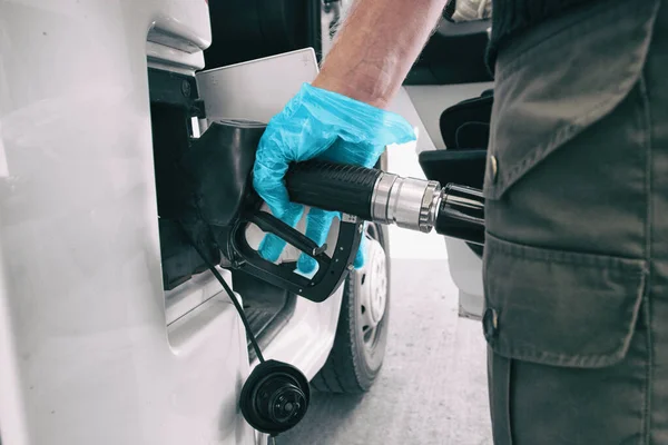 Coronavirus benzin fiyatları düşüyor benzin istasyonunda benzin pompalayan adam COVID 19 olarak mavi eldiven giyip mikroplara dokunmak için güvenlik önlemi alıyor. — Stok fotoğraf