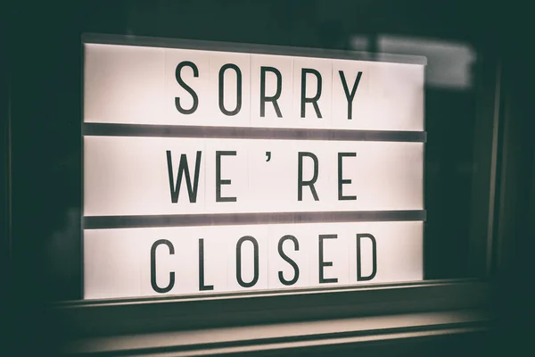 SORRY WERE CLOSED storefront window sign. Coronavirus Closure due to COVID-19 message board in business retail store lightbox at night. Shutdown of restaurants, stores, non essential services