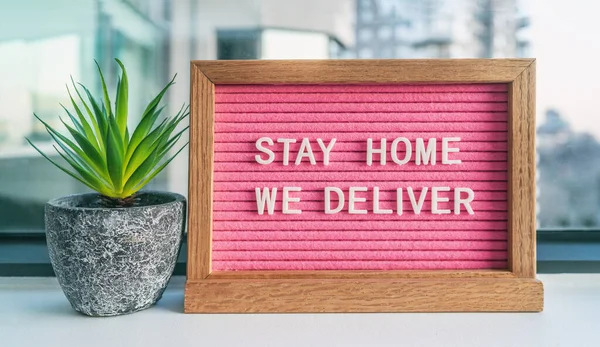 COVID-19 STAY HEM VI DELIVER Coronavirus social distancing restaurant business message sign with text offering online delivery to home, stay inside. Rosa filtbräda med växt — Stockfoto
