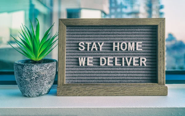 STAY HOME WE DELIVER Coronavirus social distancing restaurant business message sign. COVID-19 online delivery to home, staying inside. Grey felt board with plant — Stock Photo, Image