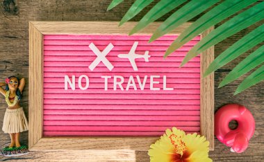 Coronavirus travelling ban sign. Travel cancelled due to COVID-19. NOT TRAVEL text written in pink felt letter board with tropical background for summer vacation clipart