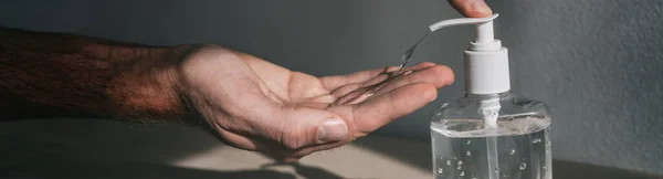Kézfertőtlenítő flakon ember használ antibakteriális gélt, hogy tisztítsa meg a kezét a koronavírus megelőzésére COVID-19 a tömegközlekedésben. Panoráma banner háttér — Stock Fotó