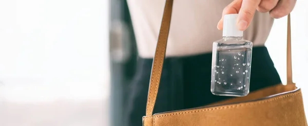 ハンドサニタイザートラベルボトルの女性は、財布COVID-19防止アルコールジェルを携帯し、手を掃除しながら外で用事をします。コロナウイルスパンデミックバナーパノラマヘッダー — ストック写真