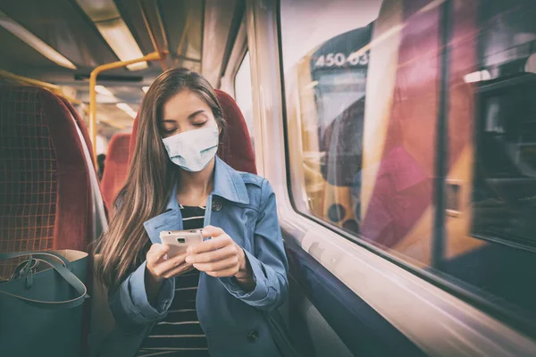 Tren istasyonu ve otobüs gibi halka açık yerlerde maske takmak zorunludur. Cep telefonu kullanan Asyalı kadın yolcu kapalı alanda otururken giyer. — Stok fotoğraf