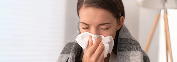 Sjuk kvinna mår inte bra hemma. Ung flicka med influensasymtom hosta i vävnad som täcker näsan när nysningar som COVID 19 förebyggande. Panoramagröda — Stockfoto