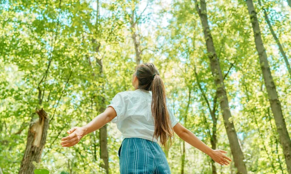 Svobodná žena dýchá čistý vzduch v přírodním lese. Šťastná dívka zezadu s otevřenou náručí ve štěstí. Čerstvé venkovní lesy, wellness zdravý životní styl — Stock fotografie