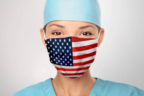 Medico americano che indossa la maschera COVID-19 pandemica di Coronavirus negli Stati Uniti d'America. Stampa bandiera americana su donne asiatiche medici maschera sorridente in confidenza dando speranza — Foto Stock