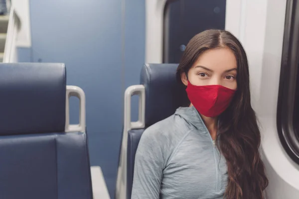 Mujer con máscara facial en el transporte público durante la pandemia de coronavirus. Máscara facial que lleva en el tren de transporte de viajeros. Pasajero multiracial mujer que usa cubierta bucal de tela en los desplazamientos — Foto de Stock