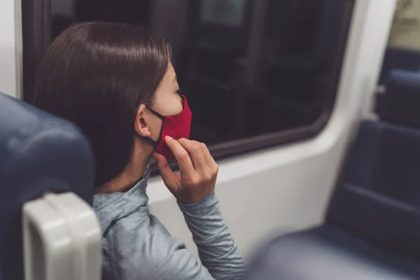 Cubierta facial obligatoria en el transporte público durante la pandemia de coronavirus. Mujer viajera poniéndose una máscara de tela. Pasajero tocando la tapa de la boca en el viaje — Foto de Stock