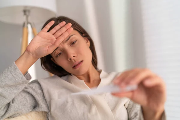 Coronavirus Aziatische vrouw controleert temperatuur met thermometer. Het corona virus veroorzaakt respiratoire aandoeningen zoals de griep met symptomen zoals hoest, hoge koorts en in ernstigere gevallen longontsteking. — Stockfoto