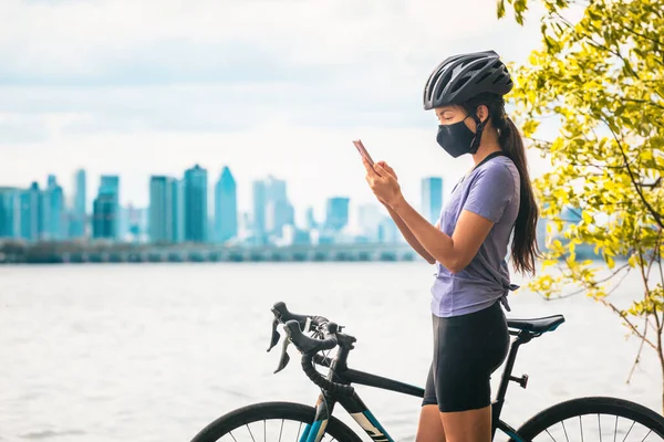 Cyklista na kole pomocí mobilního telefonu pro sledování kontaktů aplikace nošení COVID-19 obličejová maska jako prevence koronaviru při jízdě na kole venku na městské cestování dovolená ekoturistika — Stock fotografie