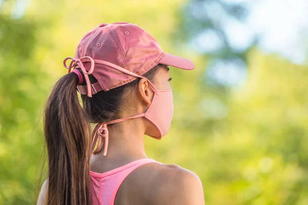 Corona virus gezichtsmasker COVID-19 jonge gezonde vrouw op outdoor wandeling met doek string stropdassen met roze sportmuts. Zomer levensstijl — Stockfoto