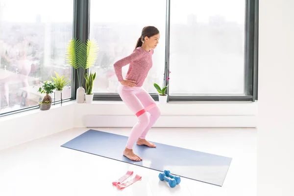 Opór band fitness home workout kobieta robi przysiady ćwiczenia za pomocą taśm pętlowych do pośladków nóg stojących ćwiczenia z paskiem elastycznym. Aktywacja mięśni pośladkowych celulolitu ud — Zdjęcie stockowe