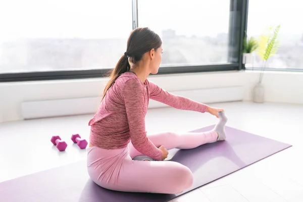 健身呆在家里锻炼女人在瑜伽训练前锻炼伸展腿肌肉。适合在晨光下在公寓客厅里锻炼的女孩 — 图库照片