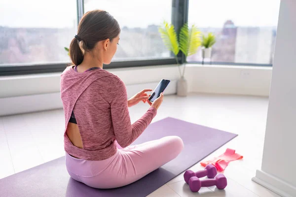Motion vistas hemma kvinna titta på fitness videor online på mobiltelefon yoga träning live streaming influencer fit flicka arbetar i vardagsrummet i lägenhet hus — Stockfoto