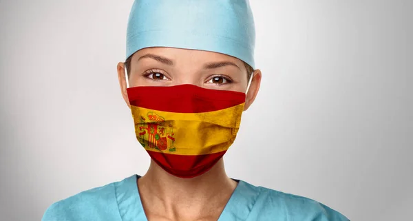 COVID-19 Pandemie in Spanien Asiatischer Arzt mit spanischem Flaggenaufdruck auf Operationsmaske. Glückliche selbstbewusste Krankenschwester, die Positivität gibt. Coronavirus in Spanien — Stockfoto