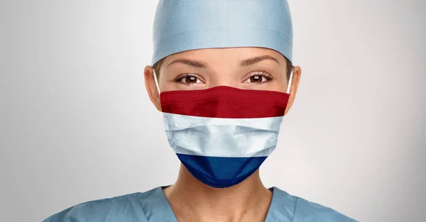 Netherlands COVID-19 Coronavirus concept. Dutch flag on happy Asian doctor medical face mask print for good recovery hope — Stock Photo, Image