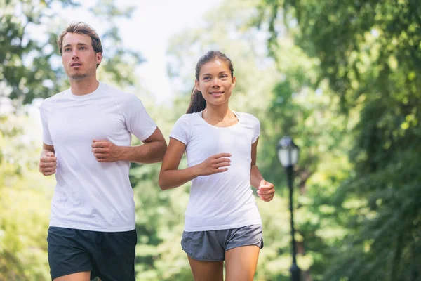 Run race runners exercising together in city park walking for charity benefit wearing white t-shirts. Sport fitness friends running together outdoor. Healthy active lifestyle Asian woman man couple Royalty Free Stock Images