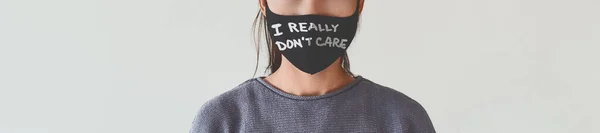 Messaggio anti-maschera I DONT CARE testo scritto sulla copertura facciale come banner di protesta silenzioso panoramico. Donna irriconoscibile che indossa maschere facciali — Foto Stock