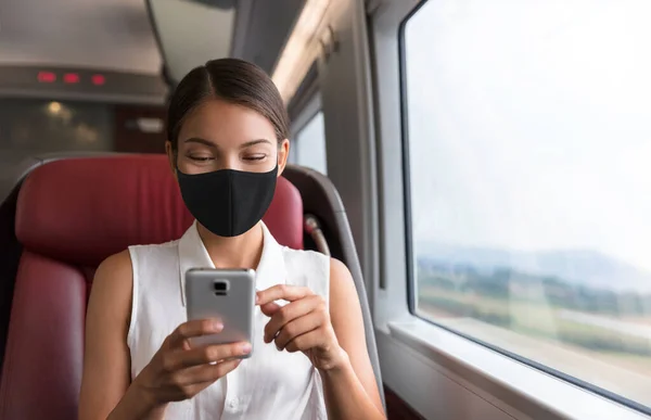 Ασιάτισσα επιχειρηματίας που χρησιμοποιεί κινητό τηλέφωνο κατά τη διάρκεια της μετακίνησης για να εργαστεί σε τρένο δημόσιων μεταφορών φορώντας μάσκα προσώπου για την πρόληψη του ιού της κορώνας — Φωτογραφία Αρχείου