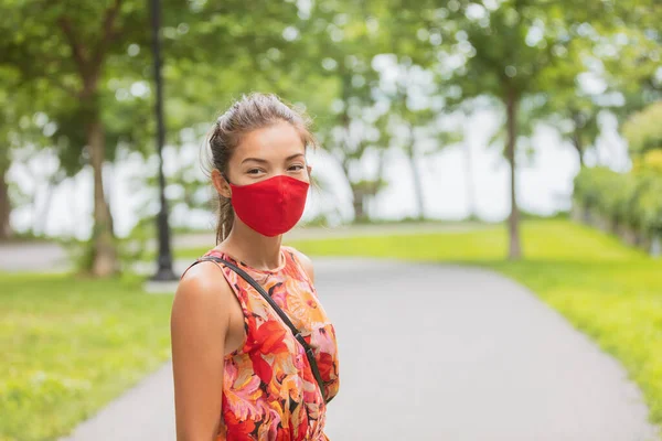 Mujer asiática con cubierta facial caminando por la calle mientras espera fuera de la parada de autobús para el transporte público. Retrato de moda de verano en máscara roja — Foto de Stock