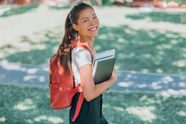 Boldog egyetemi hallgatót. Ázsiai fiatal nő mosolyog a kamerába, hátizsákkal, laptoppal, könyvvel sétál a kampuszon. Vissza az iskolába — Stock Fotó