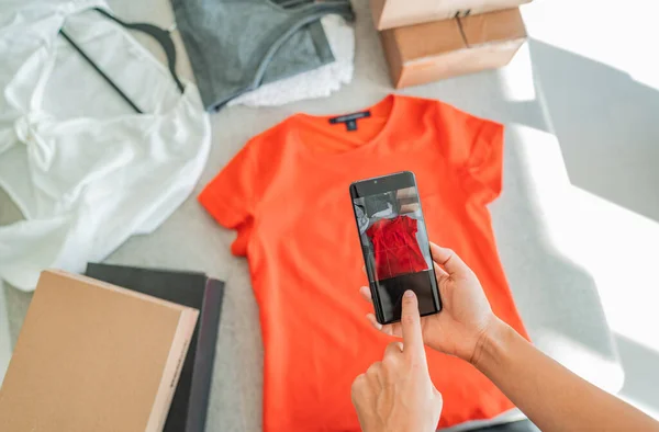 Online verkopen door het nemen van foto 's van kleding met telefoon app en het doen van e-commerce zakenvrouw thuis met verzenddozen — Stockfoto