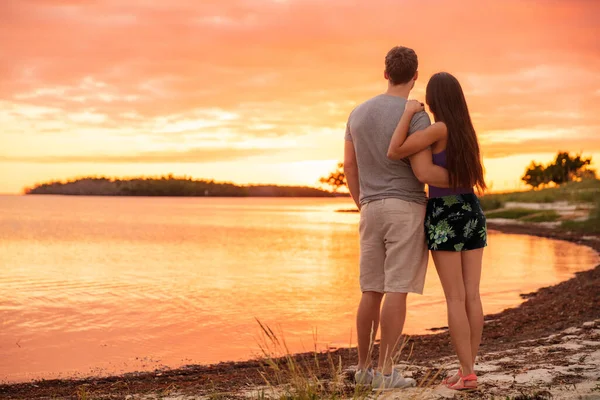 Pareja amantes disfrutando de la puesta de sol en la playa —  Fotos de Stock