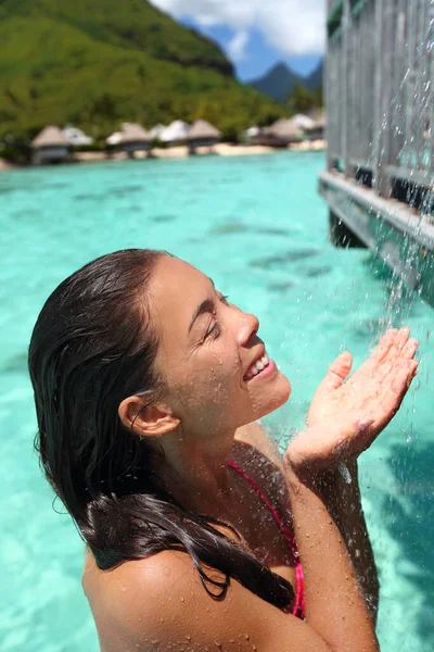 Mujer disfrutando del agua de la ducha al aire libre duchándose en el hotel privado bungalow sobre el agua en Tahití, vacaciones de viaje resort spa de lujo. Asiática chica ducha después de nadar en el océano agua — Foto de Stock
