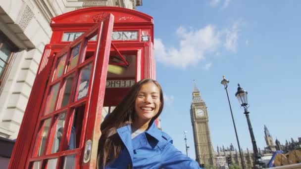 Emocionada mujer saludando con la mano diciendo hola y bienvenida en la cabina del teléfono en Londres — Vídeo de stock