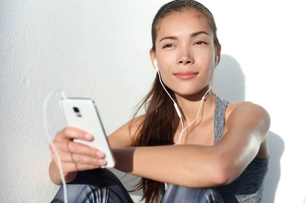 Mujer joven escuchando música de motivación con auriculares en la aplicación de teléfonos inteligentes —  Fotos de Stock