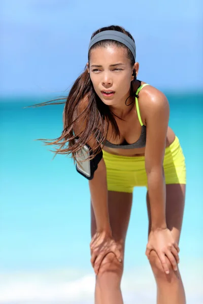 Mujer cansada corredora después del entrenamiento respirando tomando un descanso de correr en la playa —  Fotos de Stock