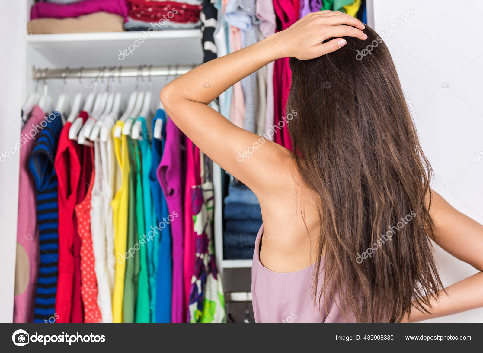 Indecision woman choosing outfit in clothes closet Stock Photo by