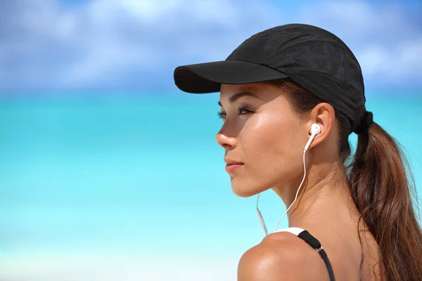 Fitness runner girl listening to music on beach — Stock Photo, Image