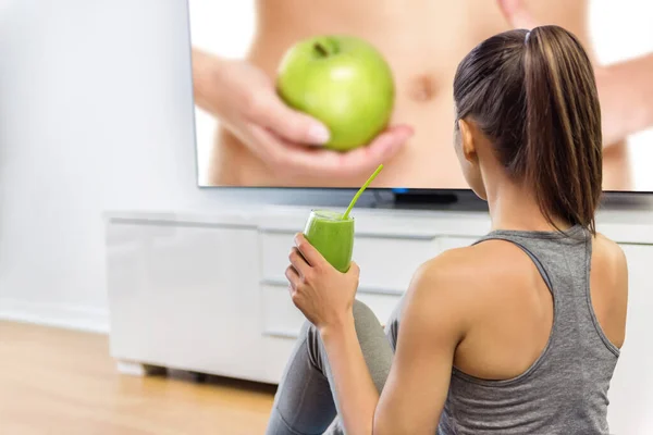 Mulher saudável bebendo smoothie verde assistindo tv — Fotografia de Stock