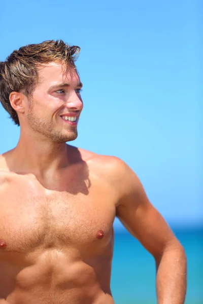 Bonito homem bonito na praia sorrindo feliz — Fotografia de Stock