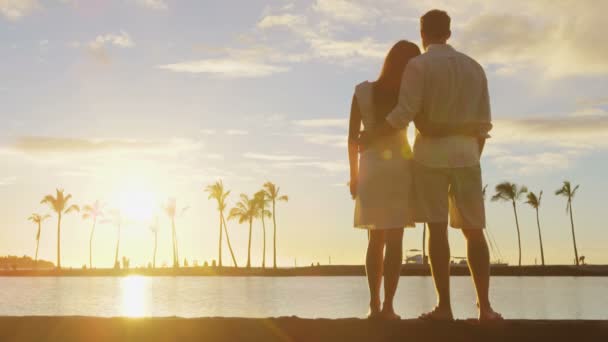 Romantický pár při západu slunce objímající se těší sledování západu slunce nad oceánem — Stock video