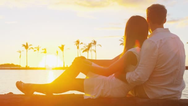 Vrouw ligt op man zitten op het strand en kijken naar de zon samen — Stockvideo