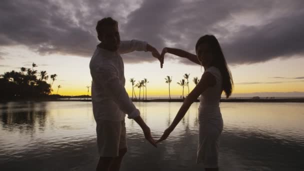 Ρομαντικό ζευγάρι στο ηλιοβασίλεμα σχηματίζοντας σχήμα καρδιάς με τα χέρια ως σύμβολο αγάπης — Αρχείο Βίντεο