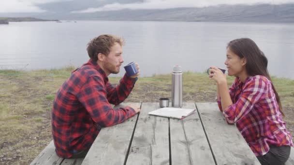 Acampar personas sentadas a la mesa tomando café junto al lago en Islandia — Vídeos de Stock